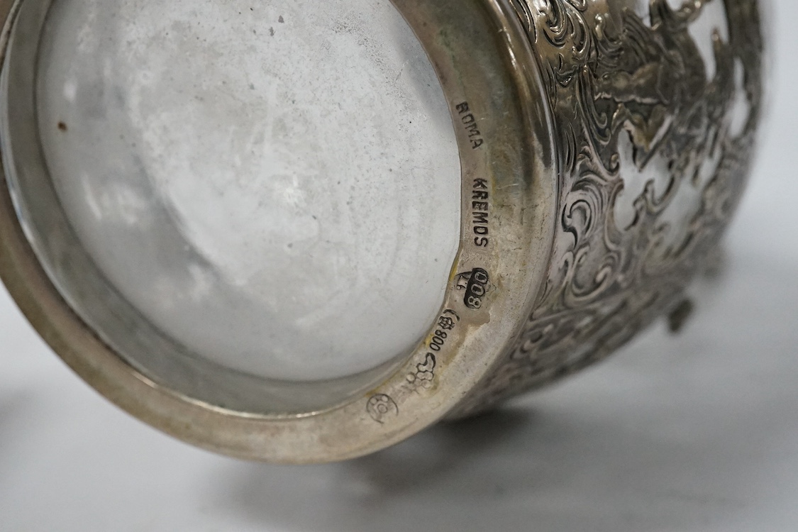 A late 19th century German pierced 800 standard white metal mounted liqueur jug, stamped Kremos, 14.4cm, a 19th century Dutch embossed 830 standard white metal trinket box and an Edwardian Hanau silver tea strainer, impo